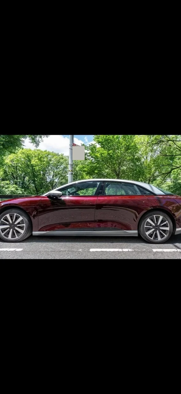 Left-side view of the burgundy 2022 Lucid Air Grand Touring parked on a street; the front is cropped.
